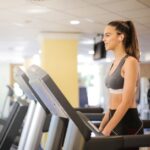 Een persoon die traint op een loopband met display in een moderne fitnessruimte, met aandacht voor de trainingsresultaten.